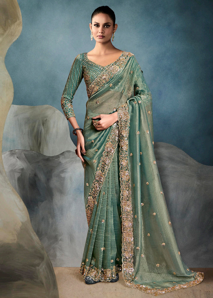 Radiant Teal Green tissue saree with intricate handwork & cutwork embroidery. Includes matching blouse piece. Perfect for wedding & festivals. Shop Now.