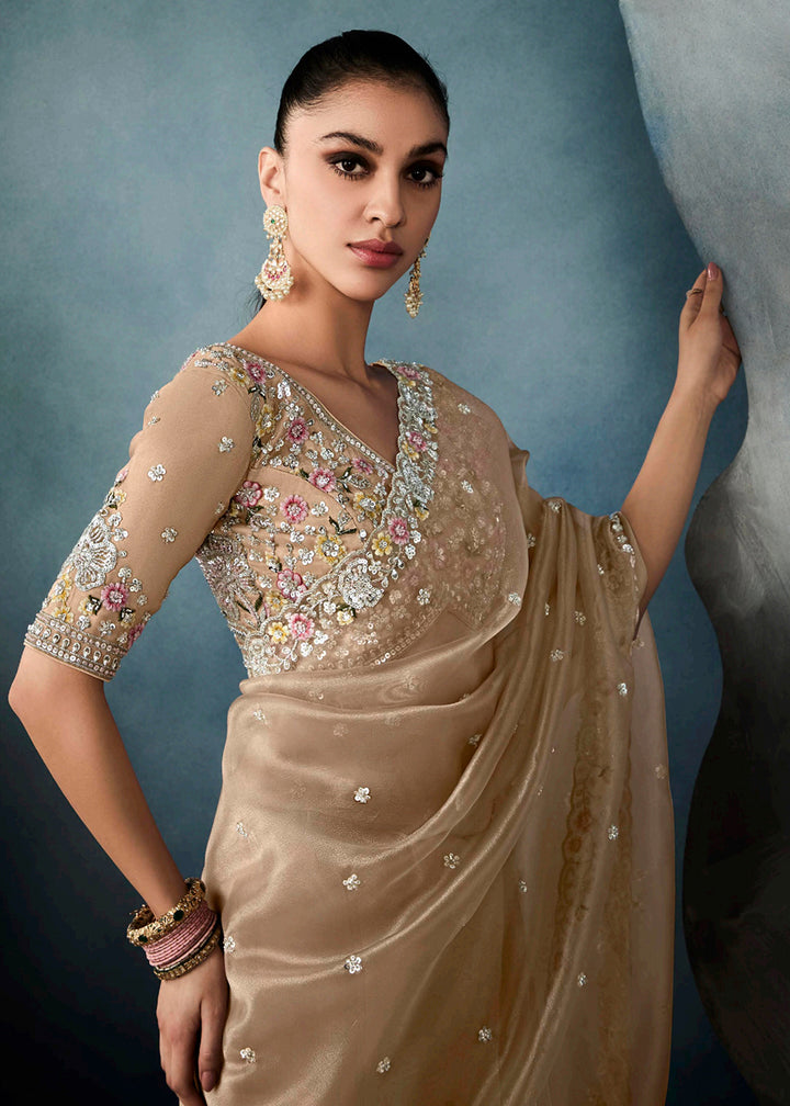 Radiant Beige tissue saree with intricate handwork & cutwork embroidery. Includes matching blouse piece. Perfect for wedding & festivals. Shop Now.