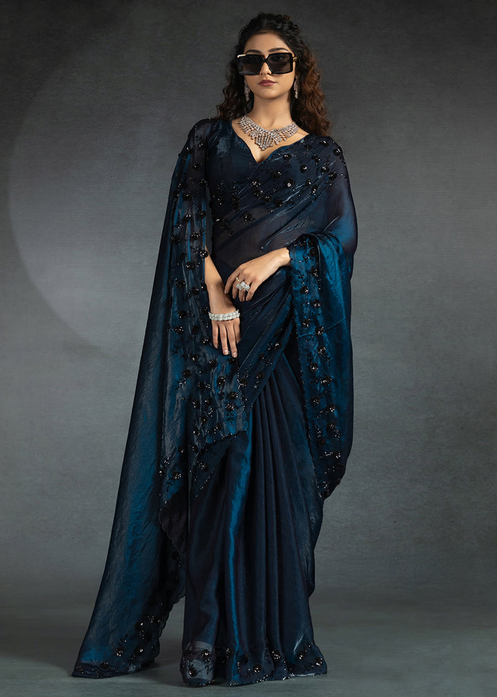 Gleaming Blue satin silk saree with intricate handwork, sequins, cutwork & zarkan embroidery. Includes matching blouse piece. Perfect for wedding parties.