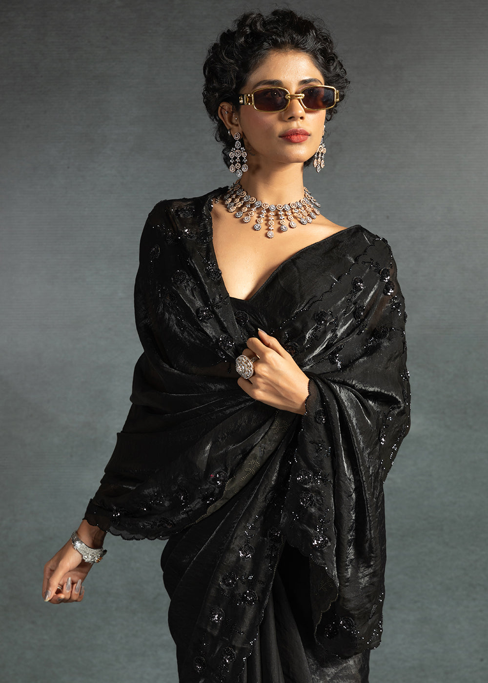 Gleaming Black satin silk saree with intricate handwork, sequins, cutwork & zarkan embroidery. Includes matching blouse piece. Perfect for wedding parties.