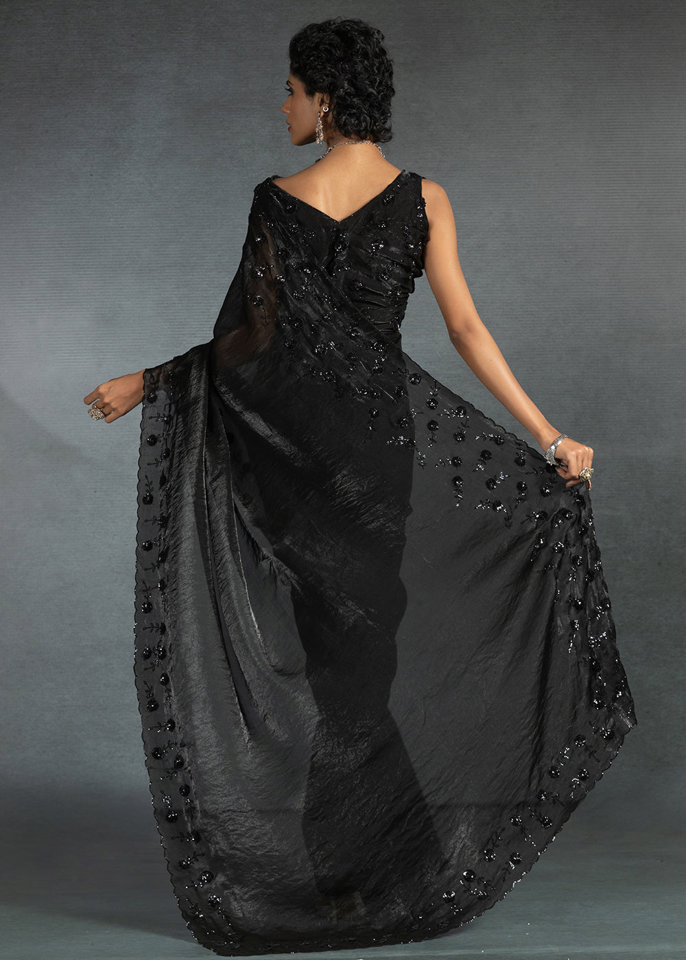 Gleaming Black satin silk saree with intricate handwork, sequins, cutwork & zarkan embroidery. Includes matching blouse piece. Perfect for wedding parties.