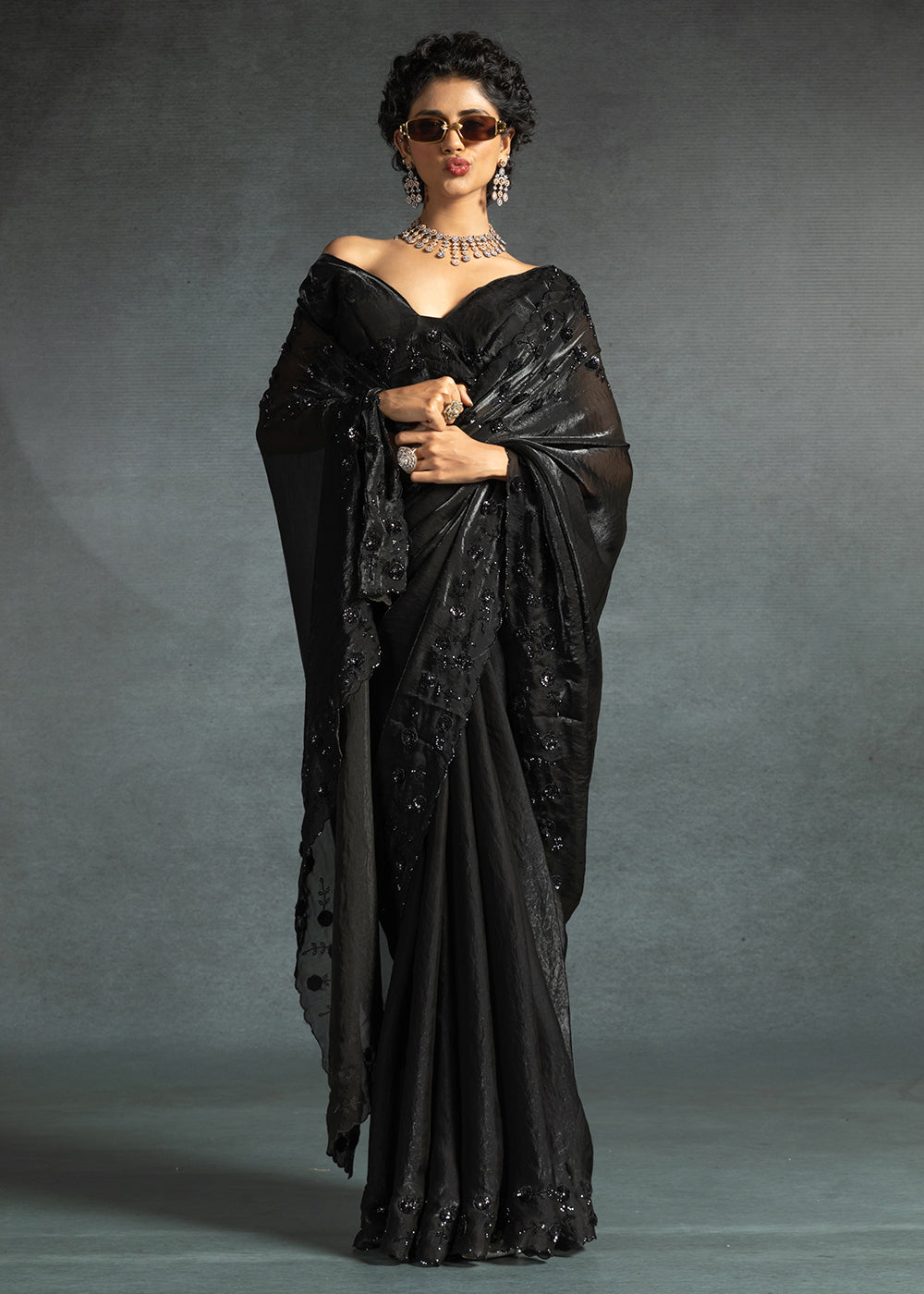 Gleaming Black satin silk saree with intricate handwork, sequins, cutwork & zarkan embroidery. Includes matching blouse piece. Perfect for wedding parties.