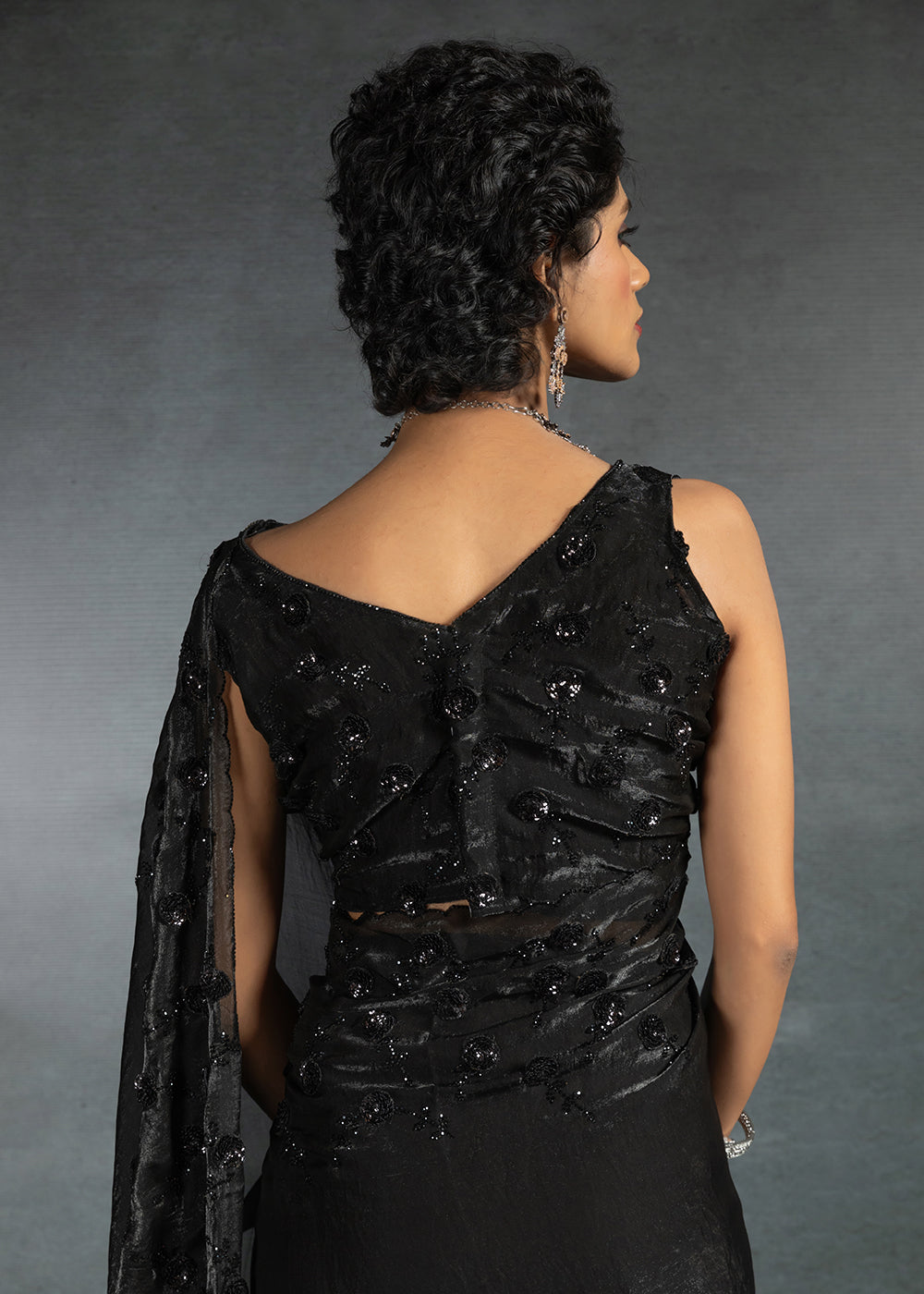 Gleaming Black satin silk saree with intricate handwork, sequins, cutwork & zarkan embroidery. Includes matching blouse piece. Perfect for wedding parties.