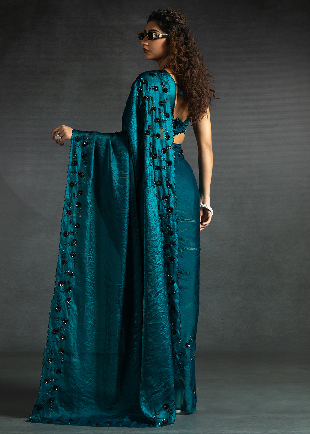 Gleaming Teal satin silk saree with intricate handwork, sequins, cutwork & zarkan embroidery. Includes matching blouse piece. Perfect for wedding parties.