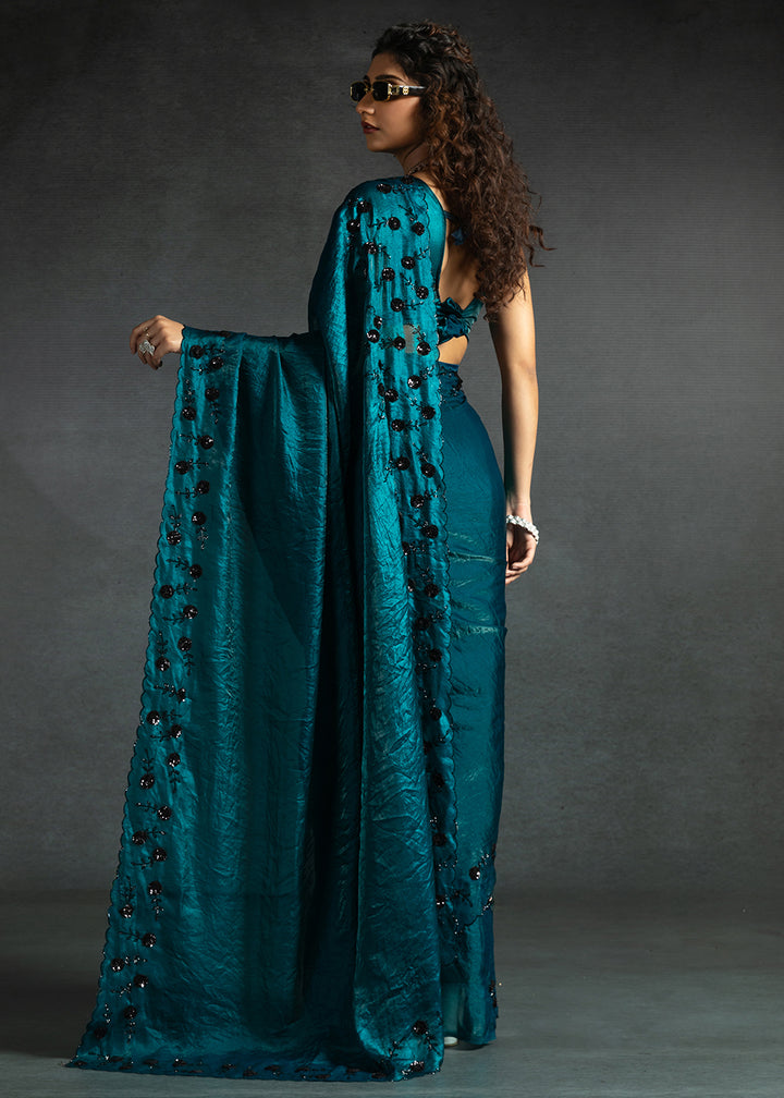 Gleaming Teal satin silk saree with intricate handwork, sequins, cutwork & zarkan embroidery. Includes matching blouse piece. Perfect for wedding parties.