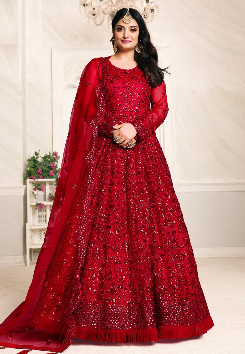 designer red anarkali dresses Radiate elegance in this stunning red gown featuring a flowy Anarkali pattern and graceful flare that moves beautifully with every step. The design is enhanced with delicate golden detailing and a stylish